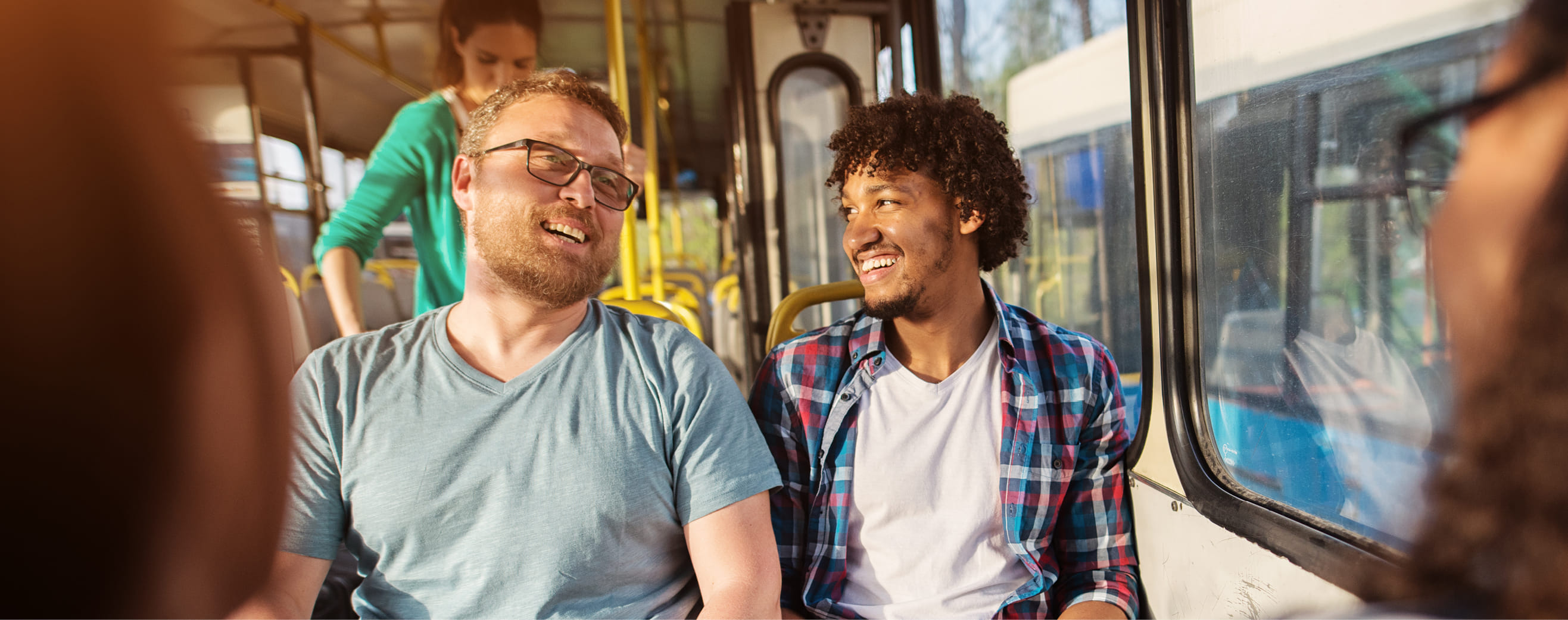 Twee mannelijke reizigers zitten in bus en glimlachen naar elkaar
