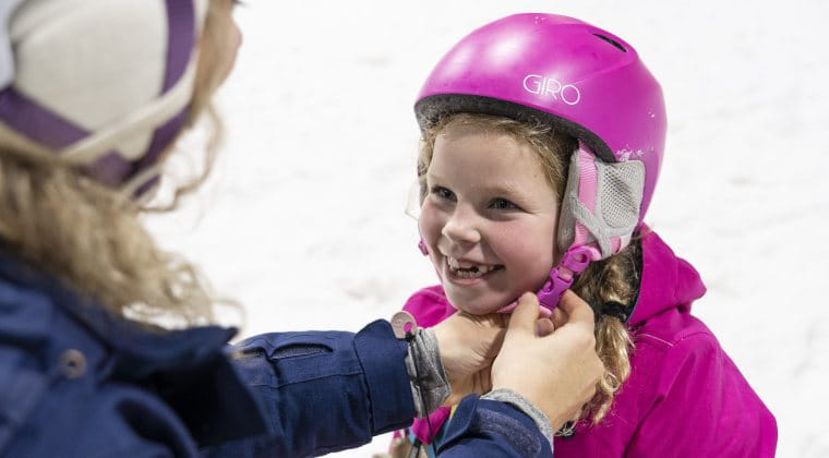 Een blij kind in de sneeuw met een paarse helm